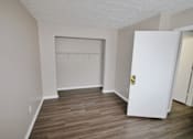 Thumbnail 6 of 13 - A room with a white door and a wooden floor.