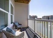 Thumbnail 26 of 31 - a balcony with two chairs and a view of an apartment complex