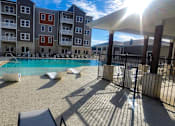 Thumbnail 5 of 31 - swimming pool with lounge chairs and umbrellas in front of an apartment building