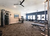 Thumbnail 18 of 44 - A gym with a variety of equipment including a treadmill, weights, and a bench.