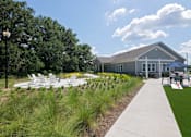 Thumbnail 28 of 44 - A building with a grey roof and white windows is surrounded by a grassy area and trees.