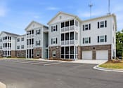 Thumbnail 51 of 51 - A large white apartment building with a parking lot in front.