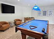 Thumbnail 7 of 24 - A pool table is in the middle of a room with a blue light hanging from the ceiling.