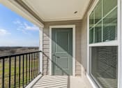 Thumbnail 7 of 25 - A balcony with a green door and a black railing.