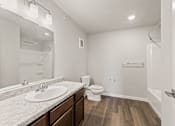 Thumbnail 8 of 25 - A white bathroom with a sink, toilet, and a mirror.