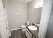 Thumbnail 17 of 18 - A bathroom with a toilet, sink, and mirror.