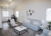 Thumbnail 1 of 18 - A living room with a blue couch, a white coffee table, and a white chair.