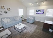 Thumbnail 2 of 18 - A living room with a grey couch, a white coffee table, and a television on the wall.