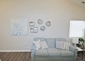 Thumbnail 3 of 18 - A living room with a grey couch and a painting on the wall.