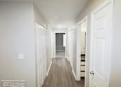 Thumbnail 8 of 18 - A long hallway with white doors and a light switch on the wall.