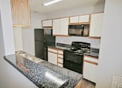 Thumbnail 6 of 18 - A kitchen with black appliances and white cabinets.