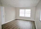 Thumbnail 5 of 18 - A room with a wooden floor and a window.