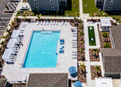 Thumbnail 52 of 83 - An aerial view of a swimming pool surrounded by a grassy area and a parking lot.