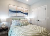 Thumbnail 42 of 83 - A bedroom with a bed, a nightstand, and a painting on the wall.