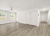 Thumbnail 5 of 33 - A room with white walls and wooden flooring with a ceiling fan.