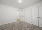 Thumbnail 6 of 33 - A room with white walls and carpeted floor with two doors.