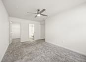 Thumbnail 8 of 33 - A room with a ceiling fan and carpeted floor.