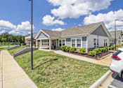 Thumbnail 32 of 33 - A building with a grey roof and white walls is surrounded by a grassy area and a parking lot.
