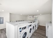 Thumbnail 22 of 33 - A row of washing machines in a laundry room.