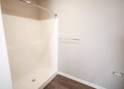 Thumbnail 12 of 15 - A white shower stall in a bathroom with a wooden floor.