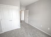 Thumbnail 10 of 15 - A room with two white doors and a carpeted floor.