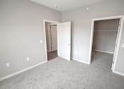 Thumbnail 13 of 15 - A room with two open doors and a carpeted floor.