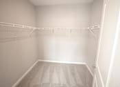 Thumbnail 14 of 15 - A white closet with a carpeted floor and a metal rack.