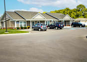 Thumbnail 4 of 15 - A building with a parking lot in front of it.
