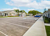 Thumbnail 7 of 15 - A parking lot with a few cars and a building in the background.