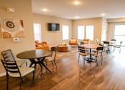 Thumbnail 6 of 15 - A living room with a TV, chairs, and a dining table.