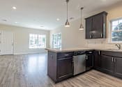 Thumbnail 4 of 12 - an open kitchen and living room with dark cabinets