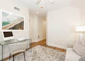 Thumbnail 9 of 31 - A room with a glass desk and a painting on the wall.