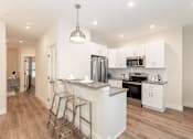 Thumbnail 4 of 31 - A modern kitchen with white cabinets and a wooden floor.