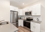 Thumbnail 5 of 31 - A kitchen with white cabinets and stainless steel appliances.