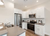 Thumbnail 22 of 31 - A modern kitchen with white cabinets and stainless steel appliances.