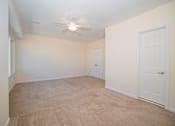 Thumbnail 9 of 12 - an empty living room with carpet and a ceiling fan
