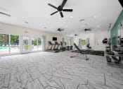 Thumbnail 10 of 14 - a gym with chairs and a ceiling fan and a pool at Hampton in Highland Apartments, Highland, IN