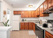 Thumbnail 10 of 19 - A kitchen with wooden cabinets and a white refrigerator at Hampton in Highland Apartments, Indiana, 46322