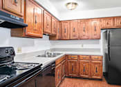 Thumbnail 9 of 19 - A kitchen with wooden cabinets and black appliances at Hampton in Highland Apartments, Indiana, 46322
