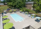 Thumbnail 18 of 28 - a swimming pool with lounge chairs and umbrellas in front of a brick building at Stonewater Apartments, Louisville, KY 40241