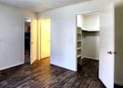Thumbnail 13 of 20 - a bedroom with wood laminate floors, white walls and a walk in closet