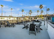 Thumbnail 46 of 64 - A patio with chairs and palm trees at Ocean Breeze Terrace Apartment, California