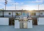 Thumbnail 53 of 64 - A white outdoor kitchen with a grill and sink at Ocean Breeze Terrace Apartment, California