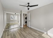 Thumbnail 11 of 64 - a living room with white walls and wood floors at Ocean Breeze Terrace Apartment, Huntington Beach, California