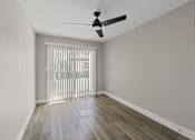 Thumbnail 12 of 64 - an empty living room with sliding glass doors and a ceiling fan at Ocean Breeze Terrace Apartment, Huntington Beach, 92648