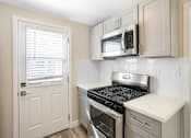 Thumbnail 5 of 10 - an empty kitchen with a stove and a microwave at Huntington Manor Homes Apartment, Huntington Beach, CA