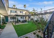 Thumbnail 36 of 64 - A patio with a table and chairs is surrounded by a green lawn. at Ocean Breeze Terrace Apartment, Huntington Beach, 92648