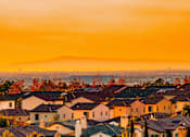 Thumbnail 6 of 10 - A sunset view of a neighborhood with houses and trees.