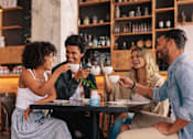 Thumbnail 8 of 10 - Four people are sitting around a table in a cafe.