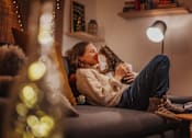 Thumbnail 10 of 10 - A woman is sitting on a couch holding a cat.